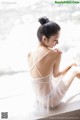 A woman in a white lingerie sitting on a window sill.