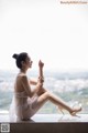 A woman sitting on a window sill with her legs crossed.