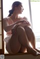 A woman sitting on a window sill with her legs crossed.