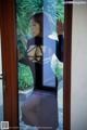 A woman in a black dress standing by a glass door.