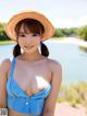 A woman in a blue bikini and a straw hat posing for the camera.