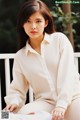 A woman sitting on a white bench wearing a white shirt.