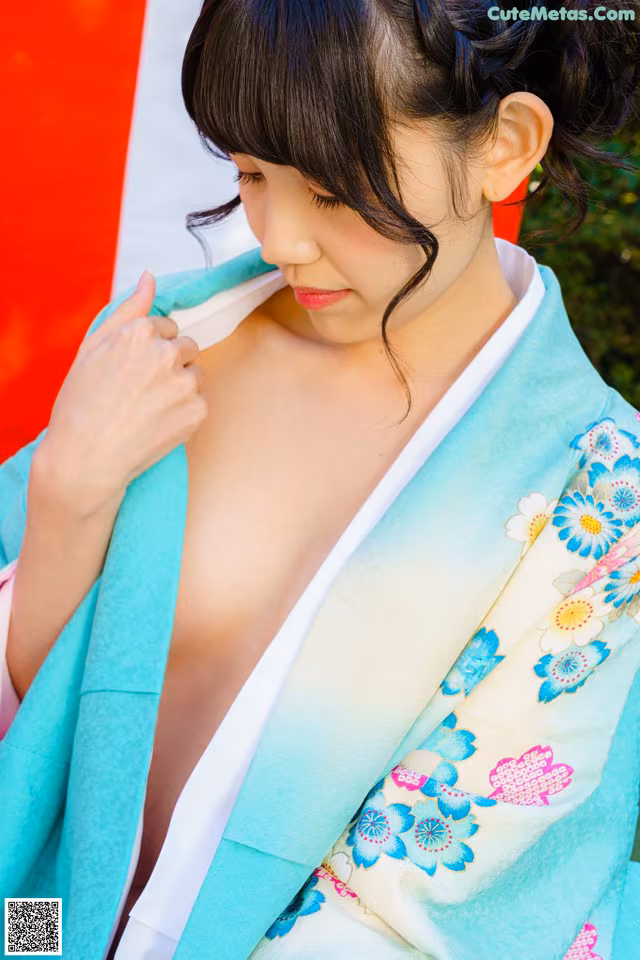 A woman in a blue and white kimono is adjusting her hair.