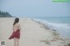 A woman in a red dress walking on a beach.