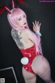 A woman with pink hair wearing a red bunny costume.