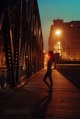 A woman standing on a bridge at night. 