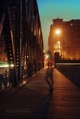 A person walking across a bridge at night. 