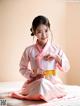 A woman in a pink hanbok sitting on a bed.