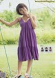 A woman in a purple dress on a swing.