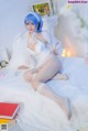 A woman with blue hair sitting on a bed.