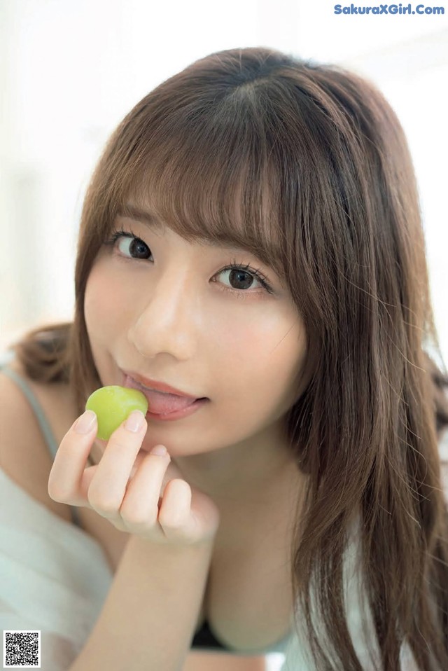 A woman holding a green apple in her hand.