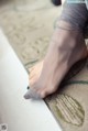 A woman is sitting on a rug with her feet up.