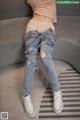 a woman sitting on top of a couch wearing ripped jeans