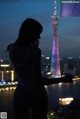 A woman standing in front of the Eiffel Tower at night.