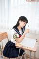 A woman sitting at a desk writing on a piece of paper.