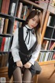 a woman sitting on top of a chair in front of a book shelf