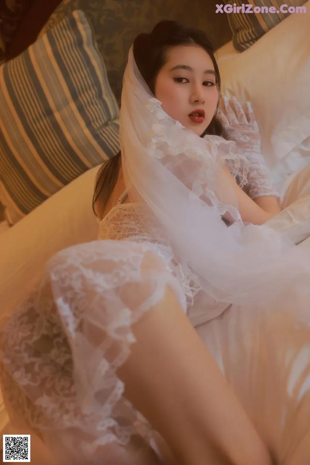 A woman in a white dress laying on a bed.