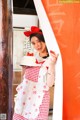 A woman in a red and white apron holding a cake.