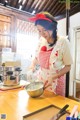 A woman in an apron preparing food in a kitchen.