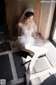 A woman in a wedding dress sitting on the floor.