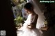 A woman in a wedding dress standing in front of a window.