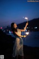 A woman holding a sparkler in her hand at night.