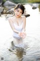 A woman in a white bathing suit is standing in the water.