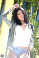 A woman in a white shirt and denim shorts posing on a swing.