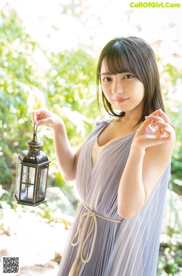 A woman in a gray dress holding a lantern.