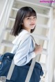 A woman in a blue shirt holding a blue bag.