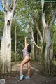 A woman in a bathing suit standing in the middle of a forest.