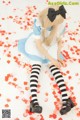 A woman in a blue and white dress sitting on a bed of rose petals.