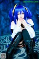 A woman with blue hair sitting on the floor.