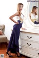 A woman standing in front of a dresser with a mirror.