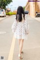 A woman walking down a street in a white dress.