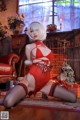 A woman in a red lingerie sitting on the floor.