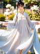 A woman in a white dress is standing in a garden.