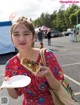 A young girl holding a plate of food in a parking lot.