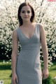 A woman in a gray dress standing in front of a flowering tree.