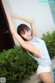 A woman in a white tank top and white shorts posing by a pool.