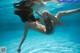 A naked woman floating in a swimming pool.