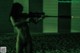 A naked woman holding a rifle in a dark room.