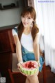 A woman sitting on a chair holding a slice of watermelon.