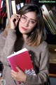 A woman holding a book in front of a bookshelf.