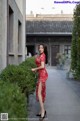 A woman in a red dress standing on a sidewalk.