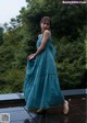 A woman in a blue dress standing on a wooden deck.