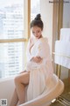 A woman in a white robe sitting in a bathtub.