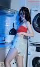 A woman standing in front of a washing machine in a kitchen.