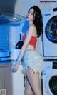 A woman standing in front of a washing machine in a kitchen.