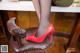 A woman in fishnet stockings and red high heels sitting on a stool.